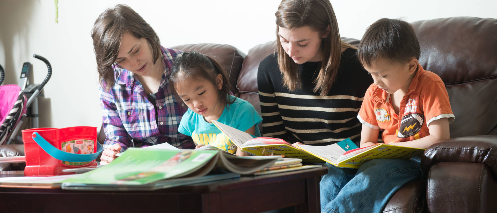 Students in a home with young kids for reading partners