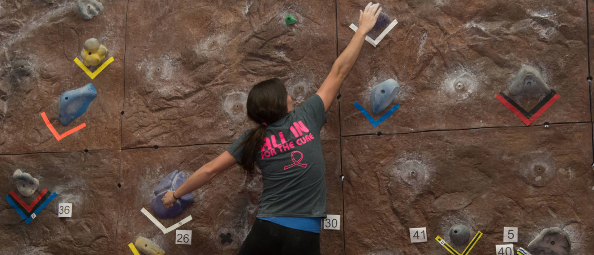 Female student climbing rock wall