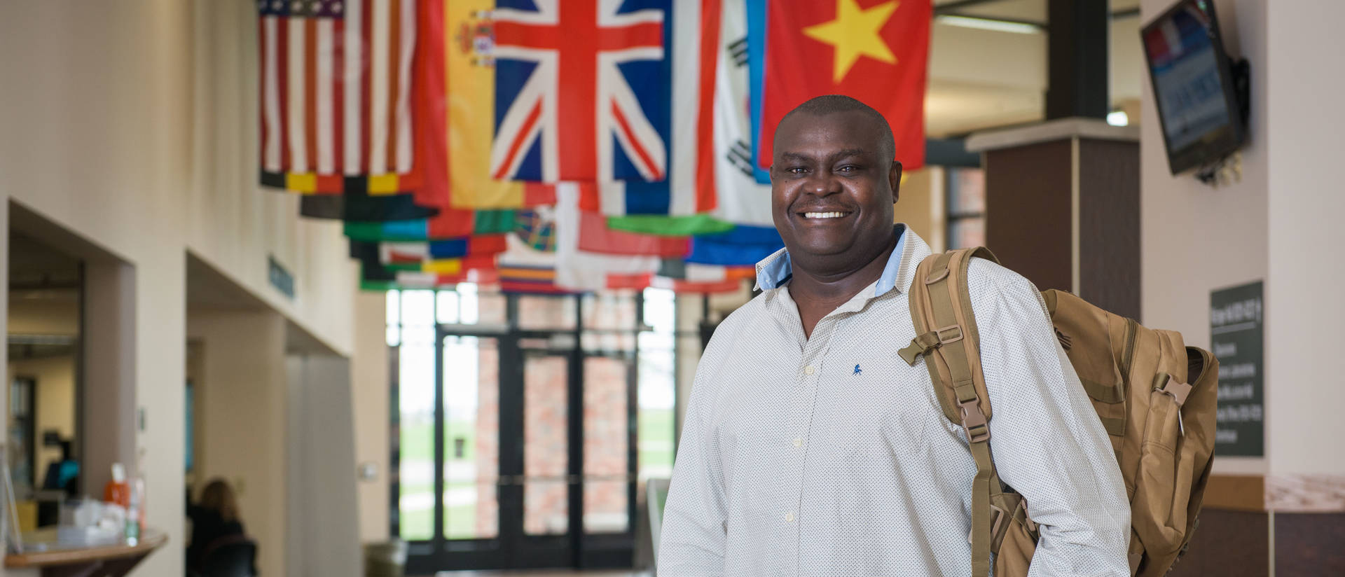 Student standing in front of flags at UW-Eau Claire – Barron County