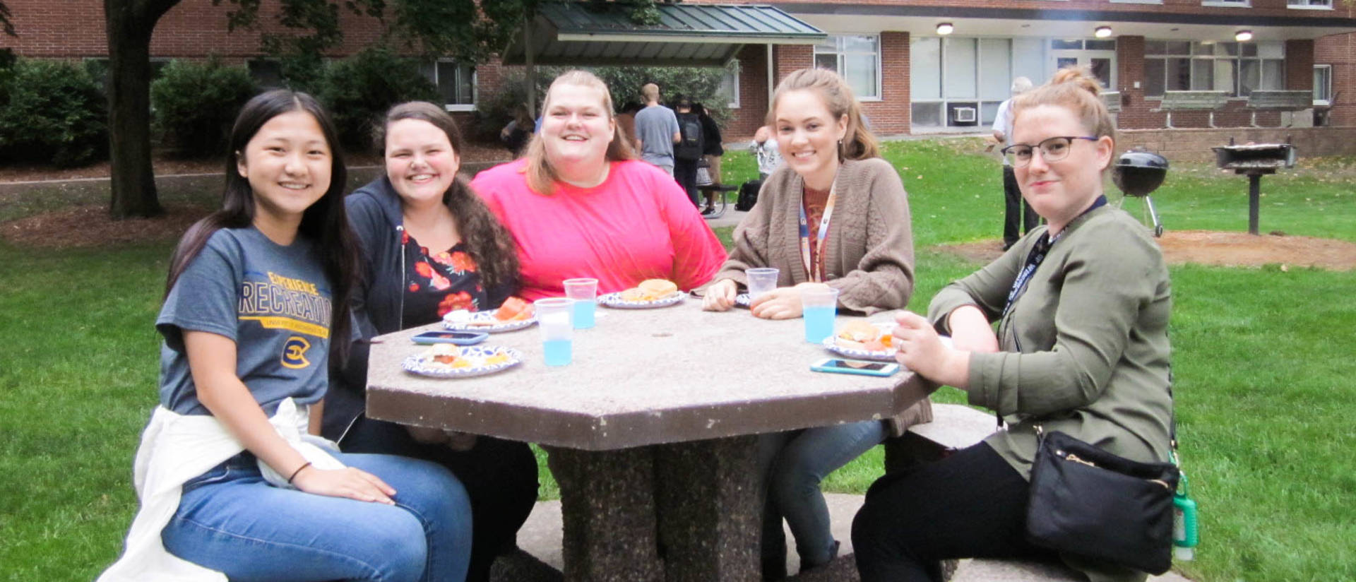 Group of four females smile at a picnic table
