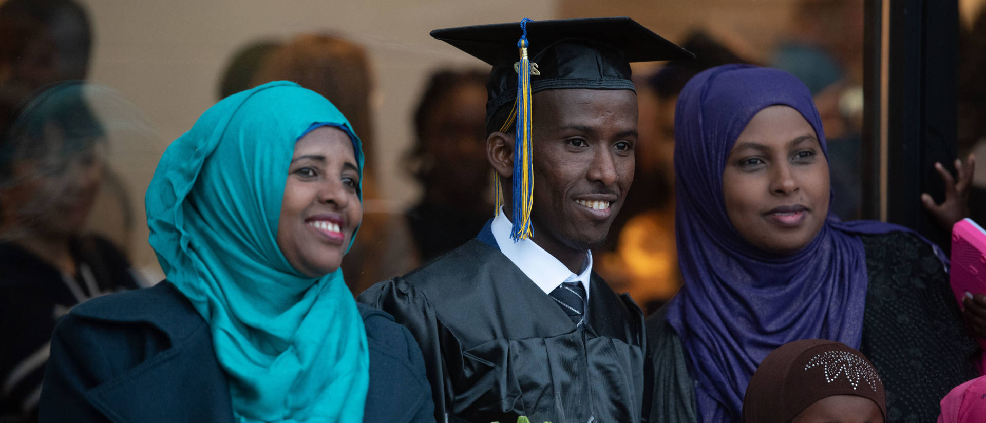 Student wearing graduation cap and gown and posing for photo with family