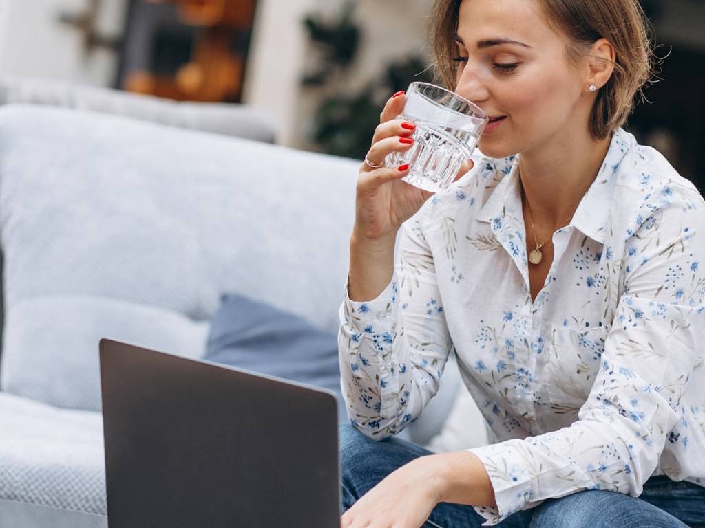 woman working on a laptop and drinking a beverage