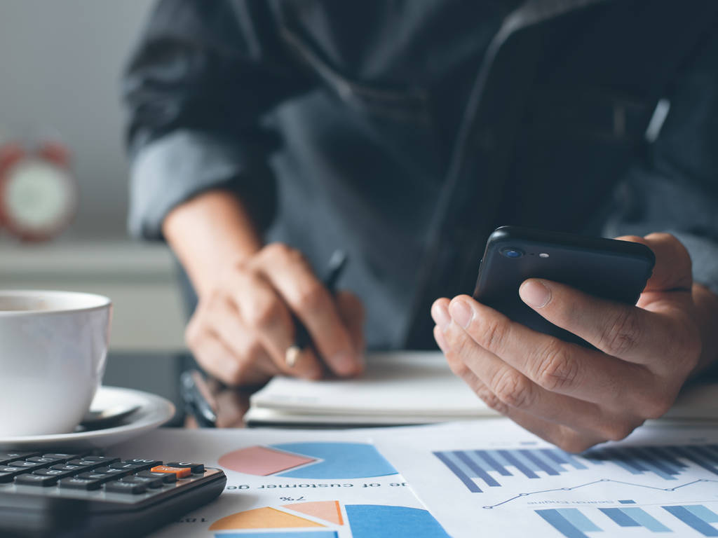 person using a cell phone and analyzing papers