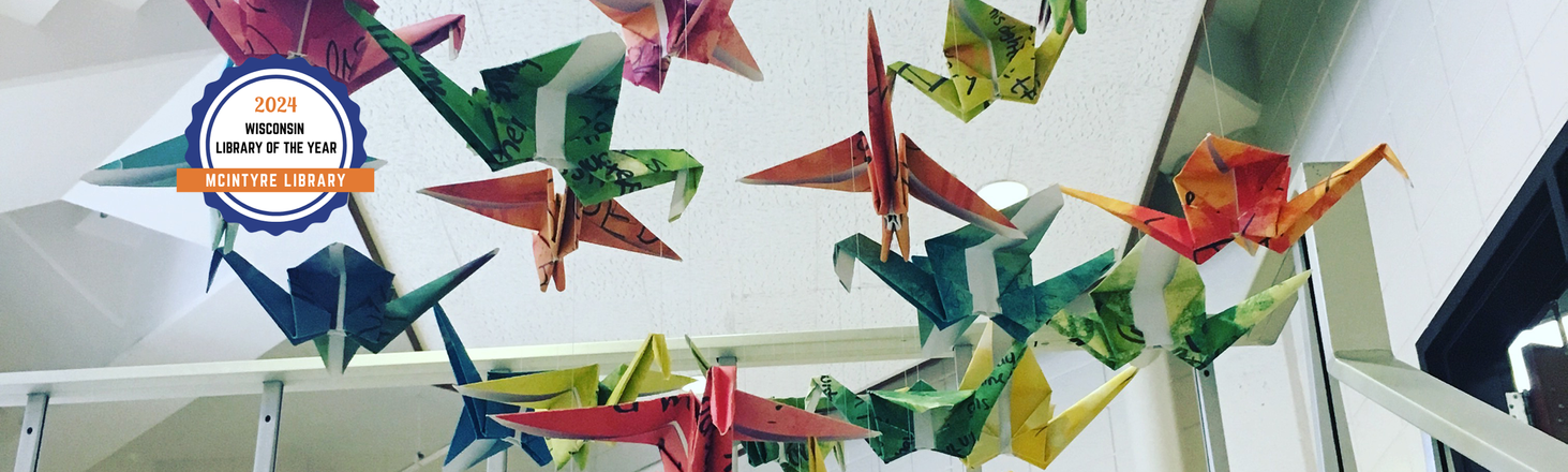 Flock of origami birds in stairwell with a badge that says Wisconsin Library of the Year 2024