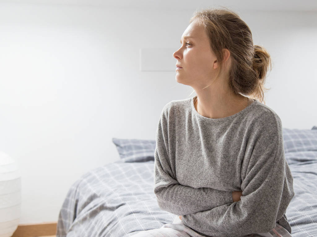 woman sitting on a bed with her arms around herself