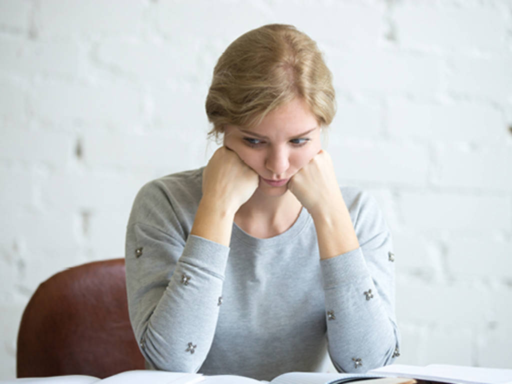 woman sitting at a table resting her head on her hands