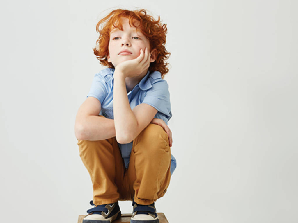 red-haired child crouching down thinking