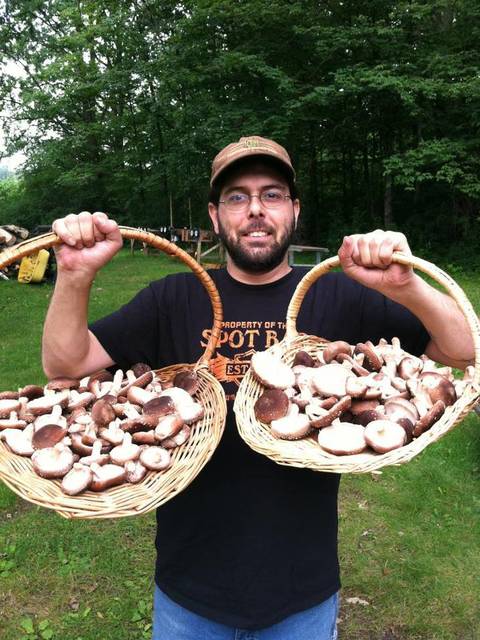 man holding two baskets of wild mushrooms