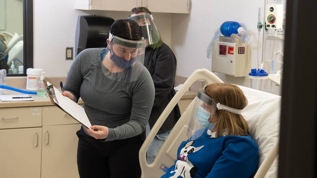 Brittney Angeli (left) and Emma Knight, both communication sciences and disorders majors, talk with a “patient” during a simulation exercise in the College of Nursing and Health Sciences’ Clinical Learning Center.
