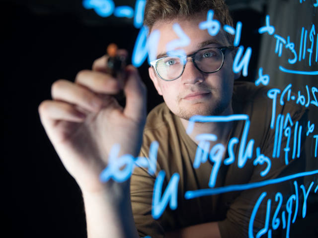 Tyler GOnzales writing on a glass light board