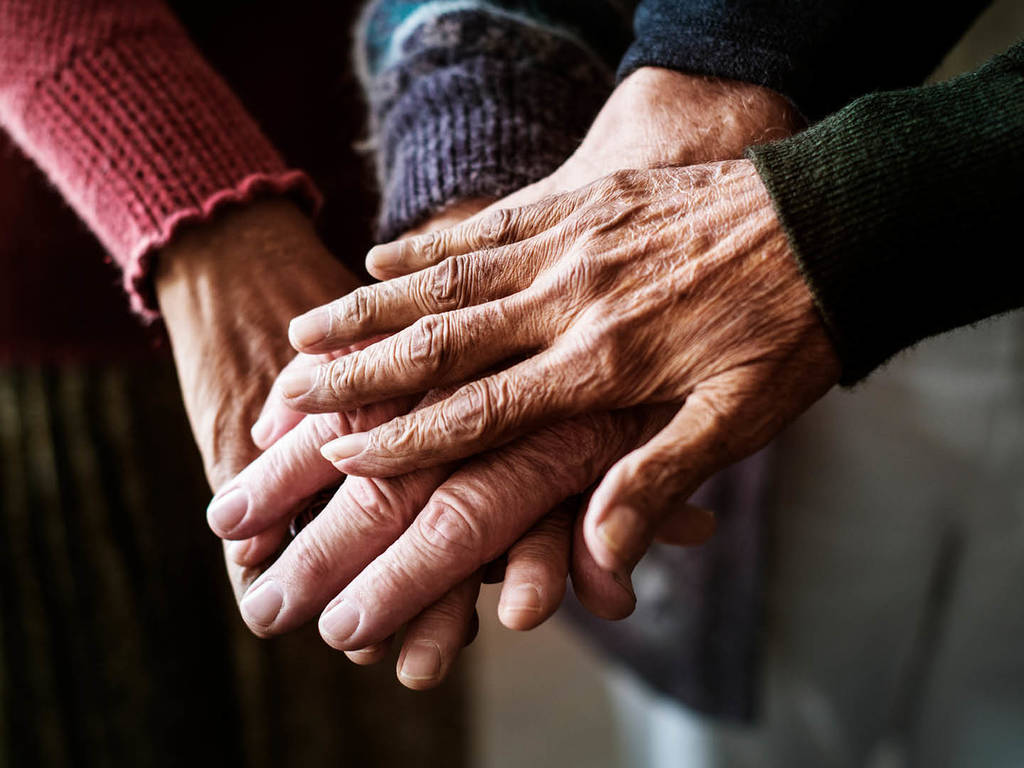 four people's hands reaching in and stacked together