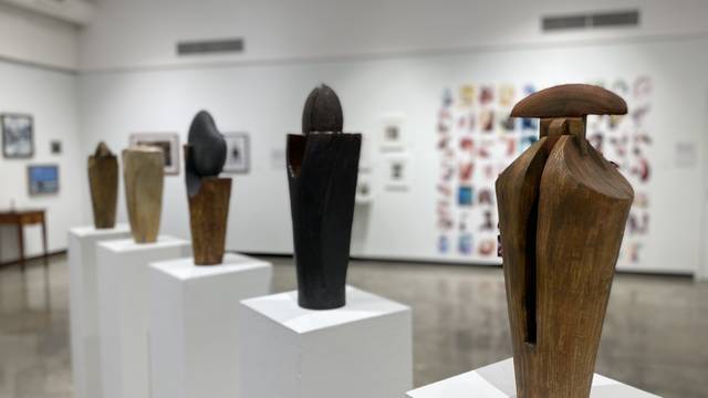 Installation view of art exhibition showing five ceramic sculptures on top of pedestals