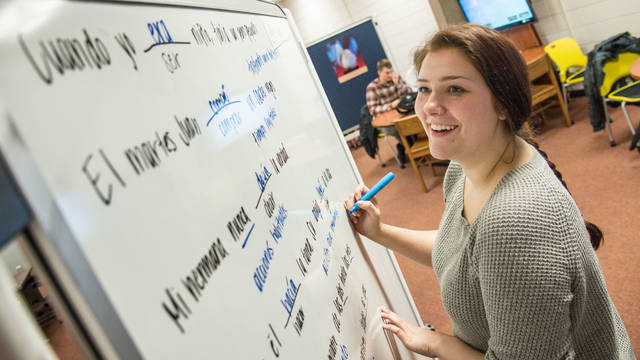 Student studying Spanish on a white board