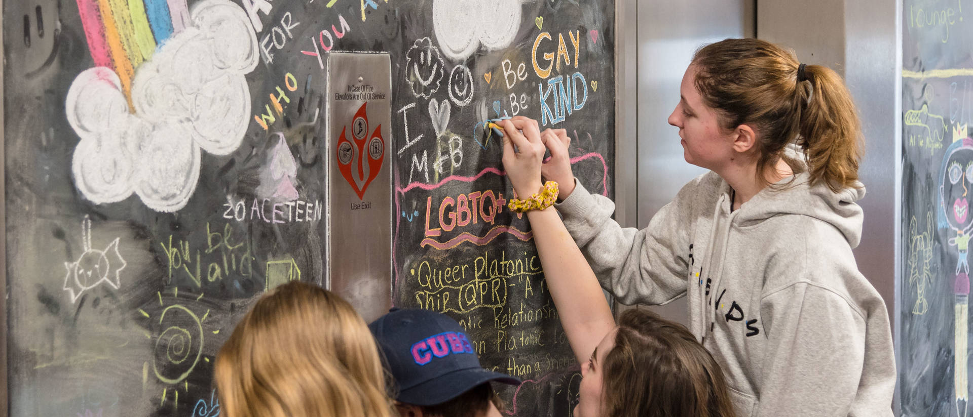 Students drawing on the chalkboard on the Rainbow Floor