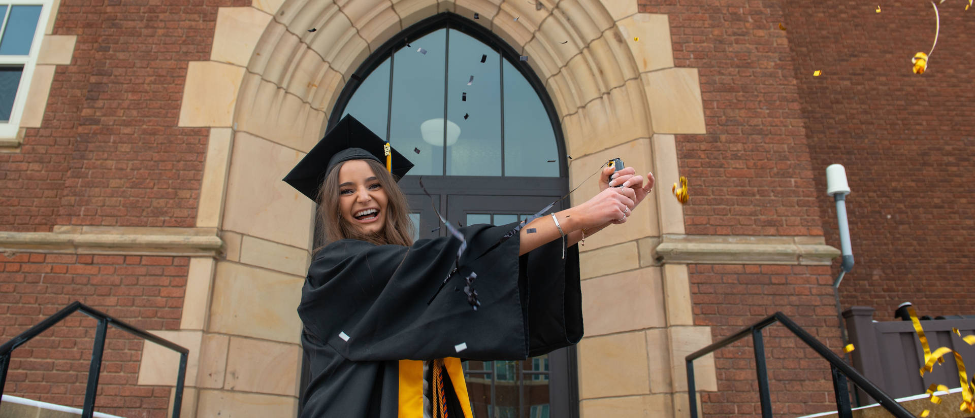 Student in front of Schofield on Commencement Day celebrating