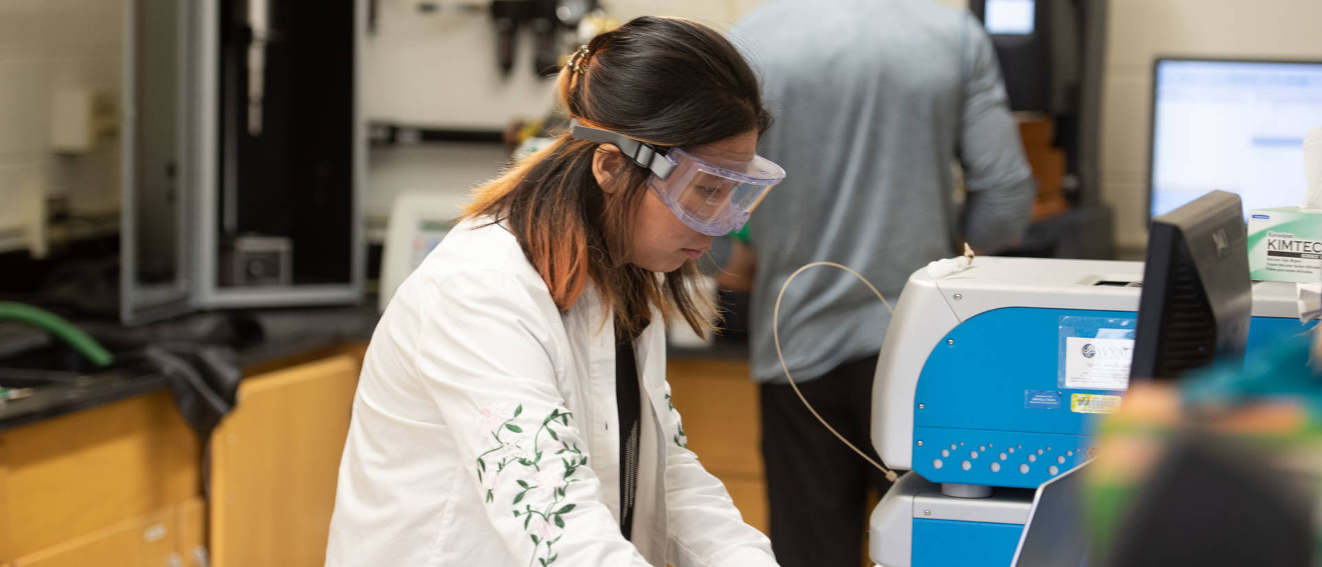 Woman in goggles working at laptop in lab.