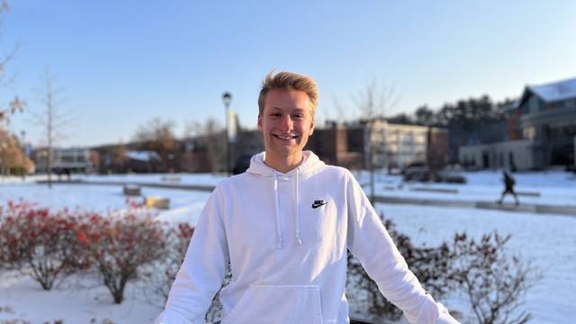 Student smiling in front of snowy campus.