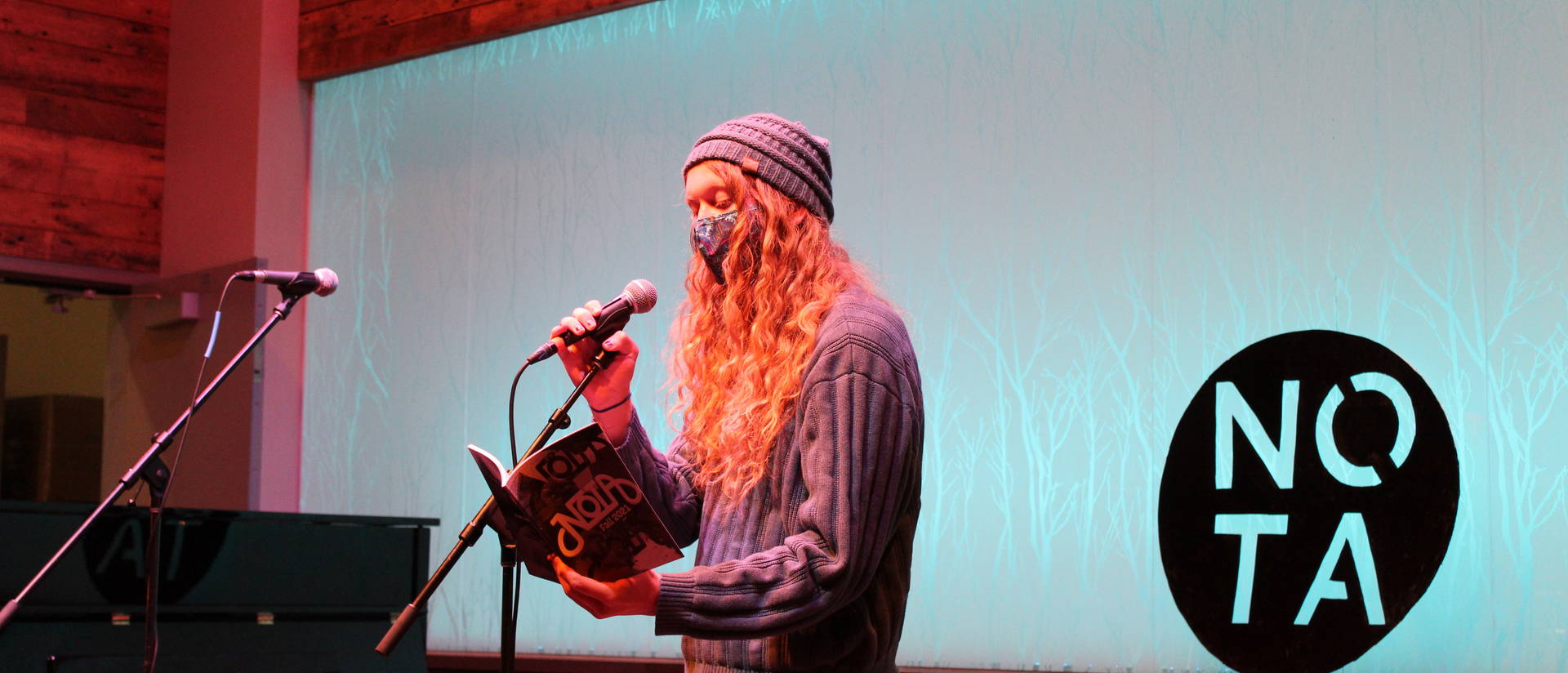 A person in a mask reading into a microphone