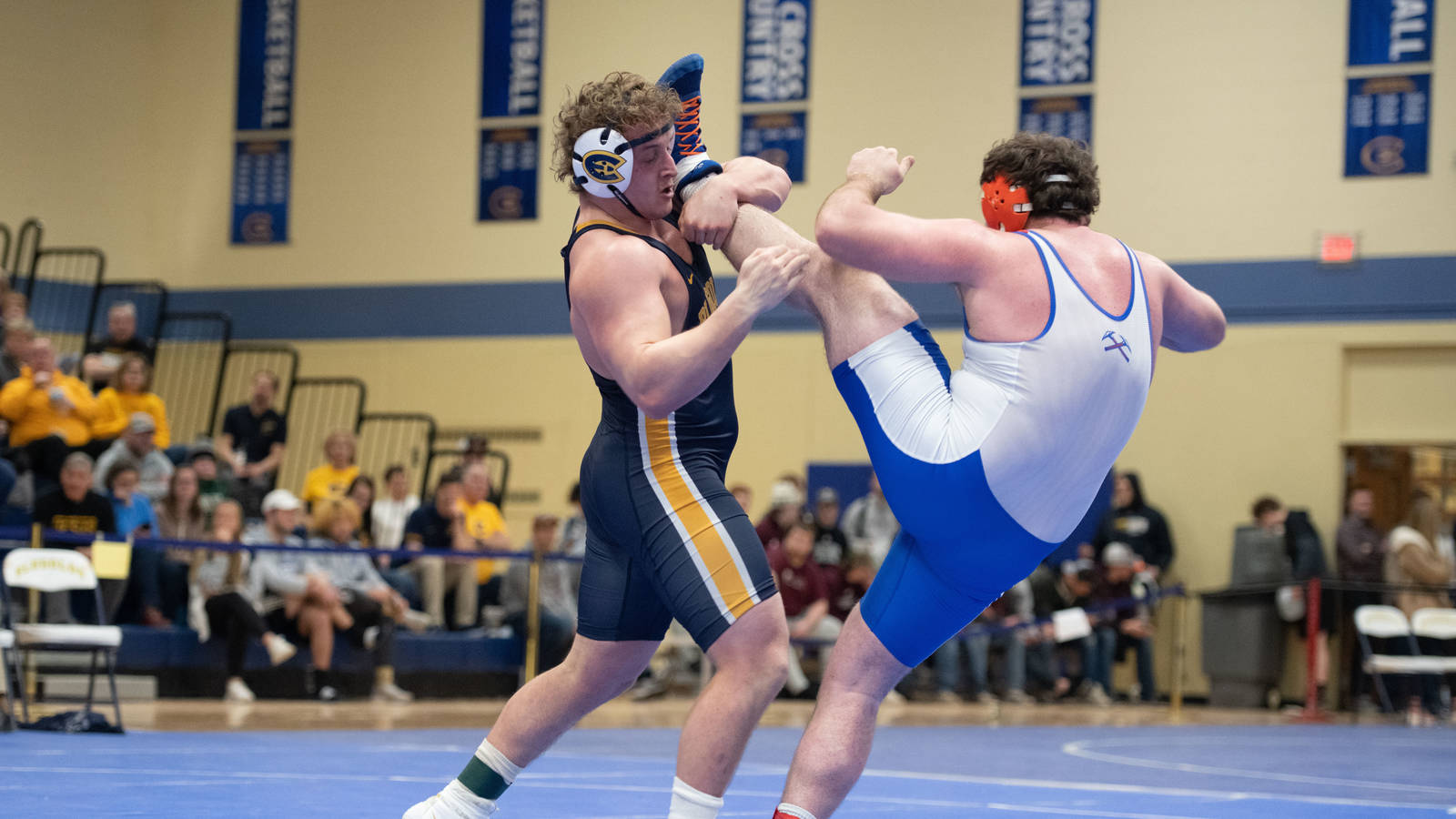 Blugold wrestler has opponent's leg over his shoulder as he works for a pin
