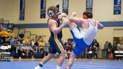 Blugold wrestler has opponent's leg over his shoulder as he works for a pin