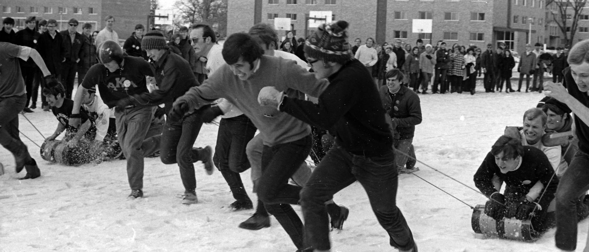 Male students competing in a sled race, ca. 1964-1971