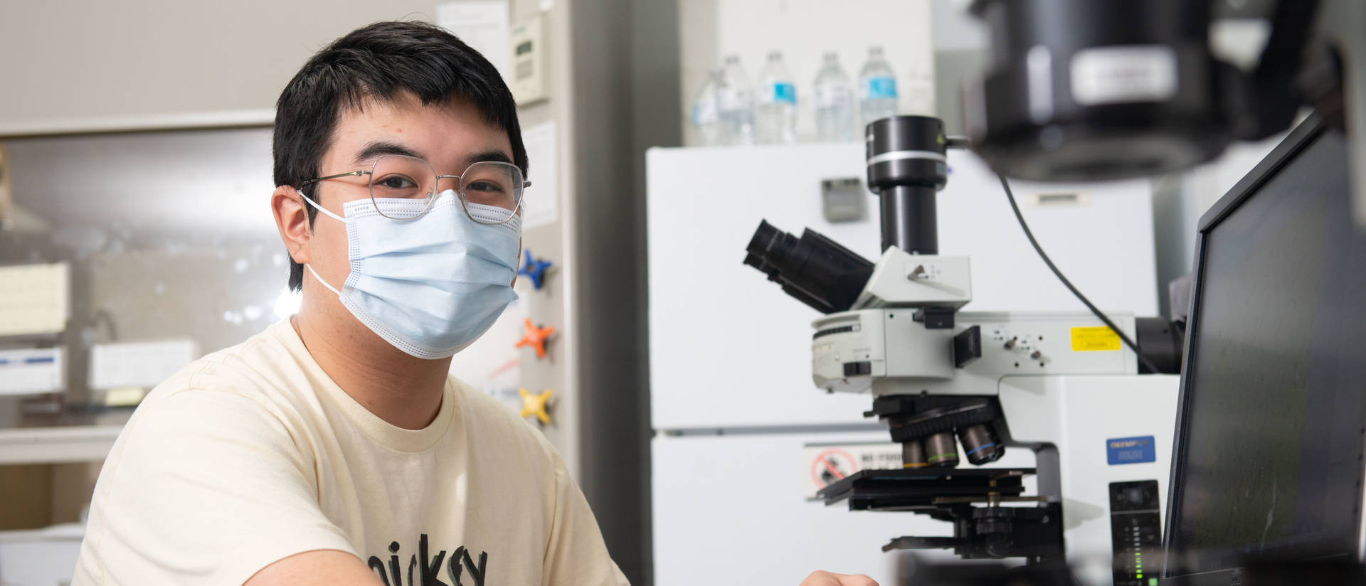 Materials science and engineering student works with a microscope in a lab on campus