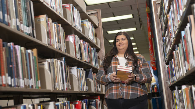 girls walking in library stacks with books