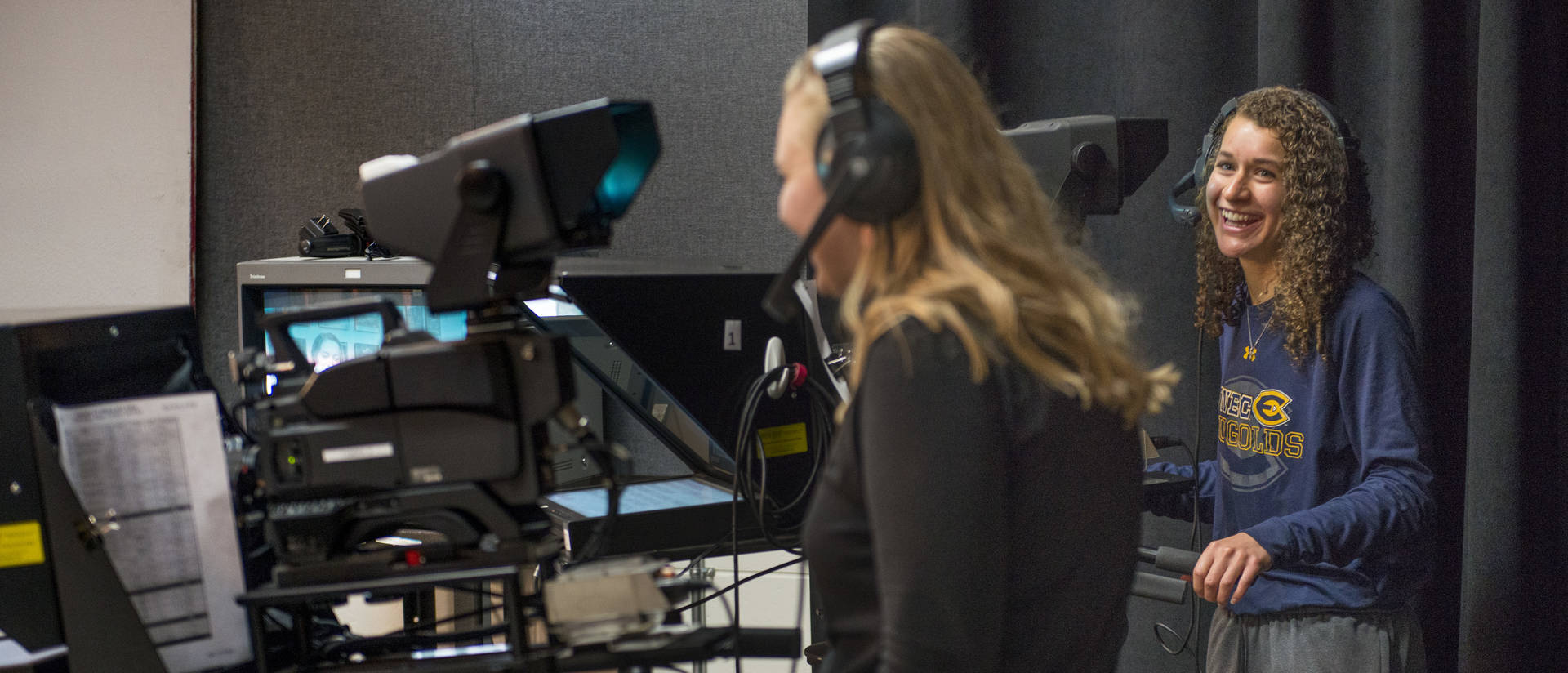 Two students work with cameras to produce a TV news broadcast in Hibbard Hall.