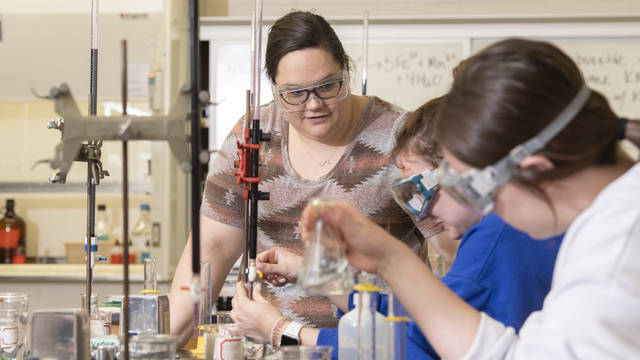 Students work on a chemistry experiment in a lab on campus.