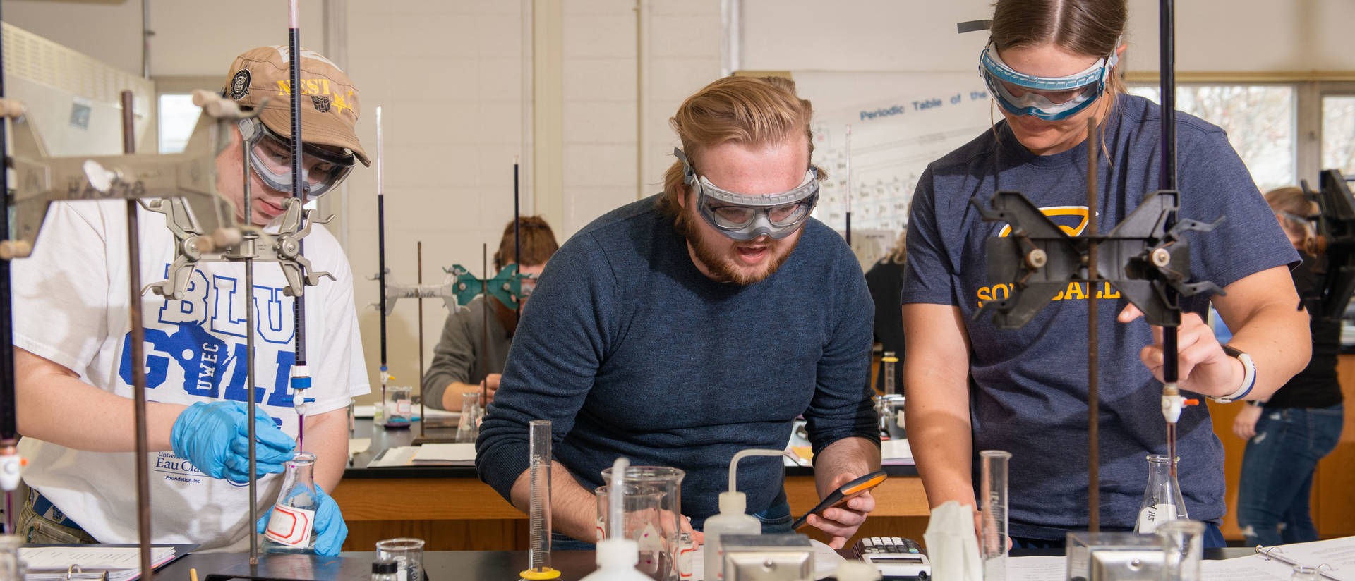 Students in a chemistry lab complete an experiment wearing safety goggles.