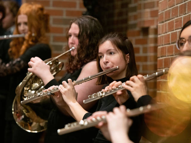 A group of students play their flutes at a musical performance.