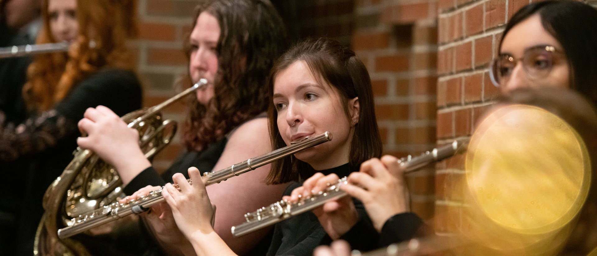 A group of students play their flutes at a musical performance.