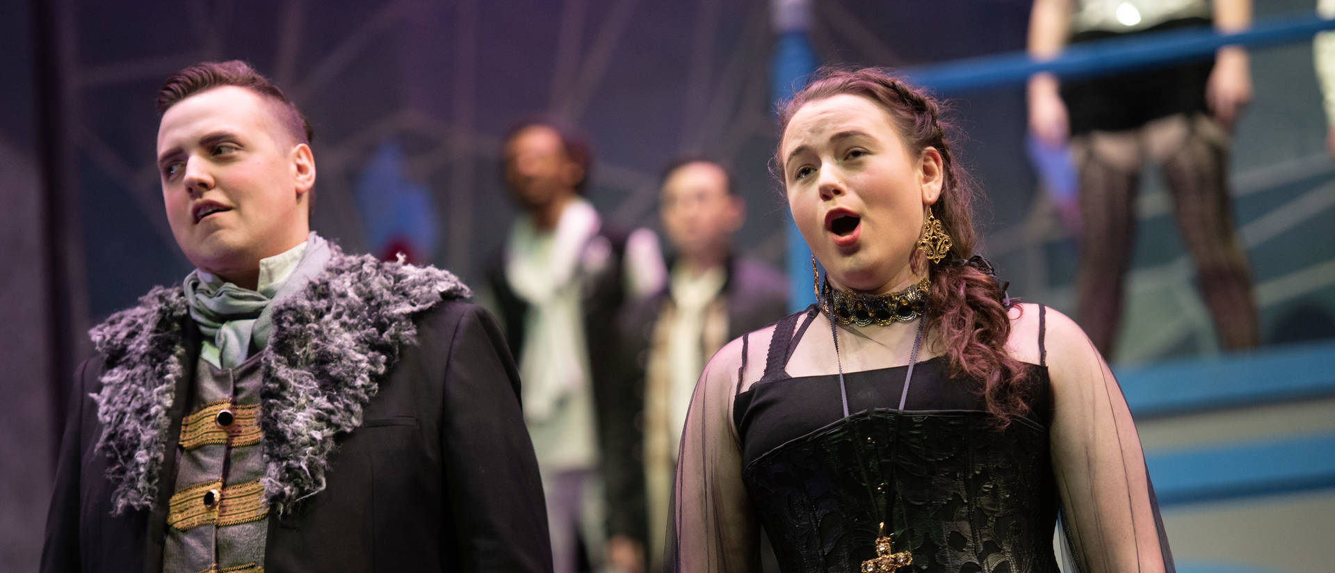 Students sing in costume on stage at a musical performance