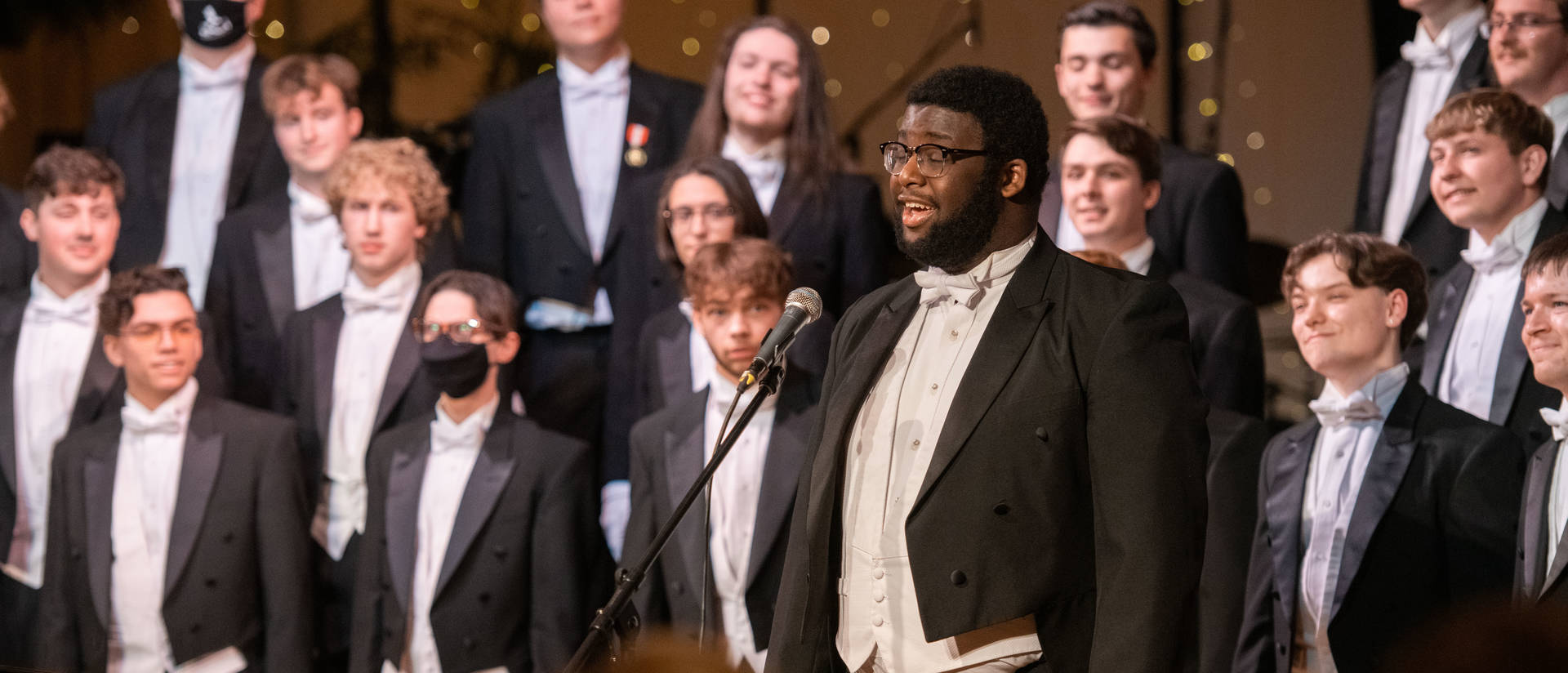 Students wearing tuxedos sing on a stage at the Viennese Ball