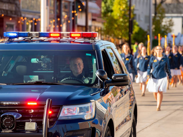 A UWEC police officer drives a police car at the front of the homecoming parade.