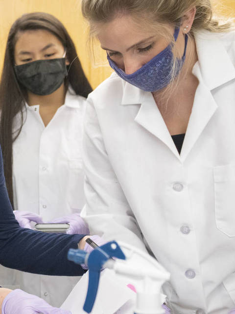 Blugolds work on research in a lab wearing lab coats and face masks