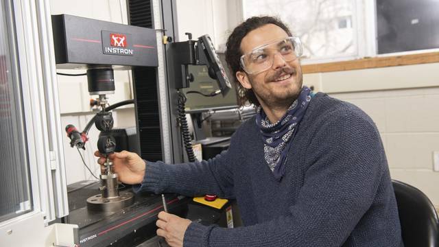 Grey Larson prepares to test the strength of new building materials using the Instron mechanical tester in the Materials Science & Engineering Center