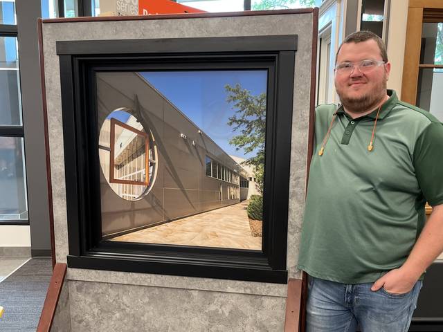 Kellan Michaelson poses with a demonstration window at Andersen Corporation