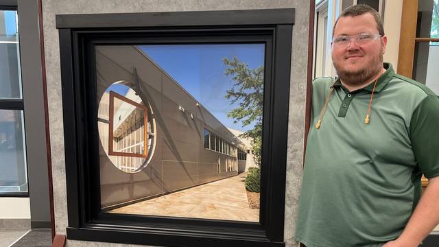 Kellan Michaelson poses with a demonstration window at Andersen Corporation