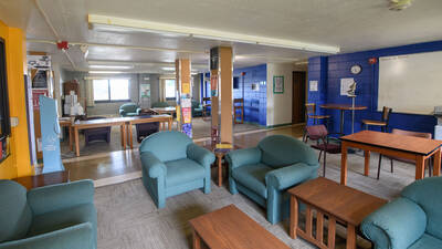 A common space area in Oakridge Hall, with armchairs and tables, plus two windows lighting the space