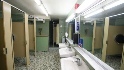 Bathroom with sinks, stalls, and showers in the distance.