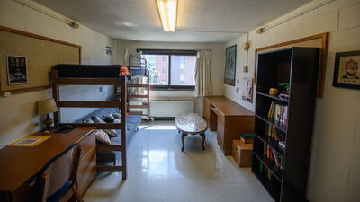 A single room in Bridgman Hall with a lofted twin XL bed, desk, book shelf, and window.
