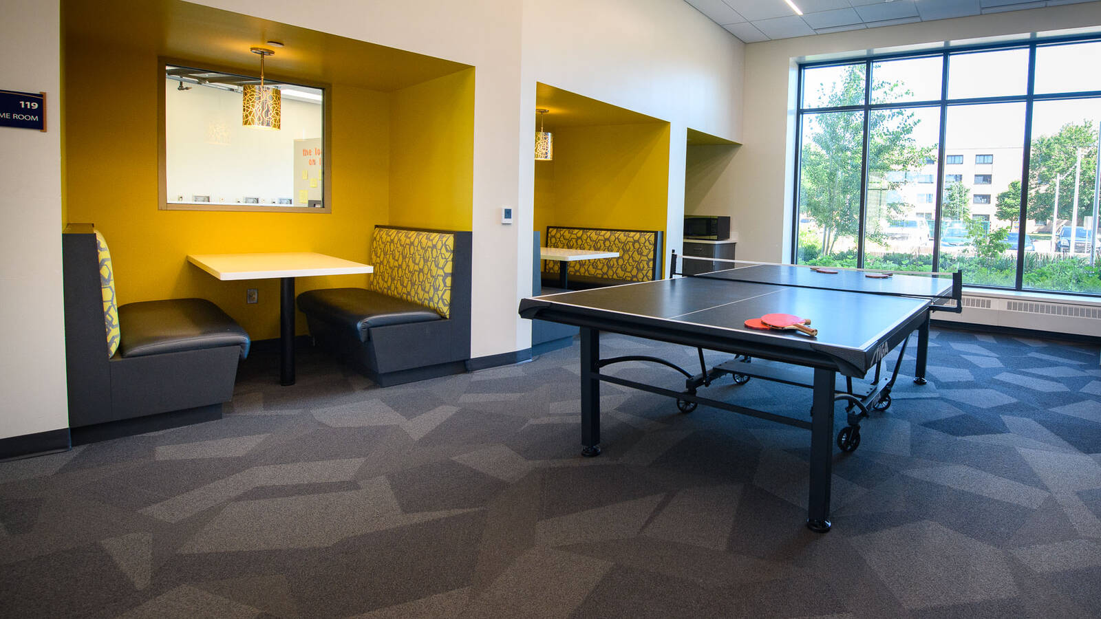 Common space in The Sites residence hall with booth-style seating and a large ping pong table