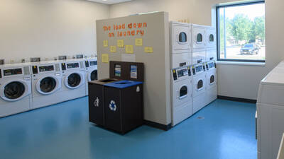 Shared laundry room showing numerous washers and dryers on the first floor of The Suites residence hall.