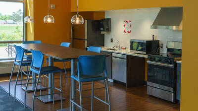 Kitchen space equipped with large refridgerator, a dishwasher, microwave and oven.