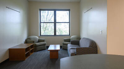 Living room space in a Chancellors Hall apartment with couches and chairs.