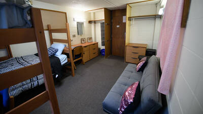 Double room in Governors Hall (viewed from wall opposite door) with two closet spaces, dressers, desks, and beds.