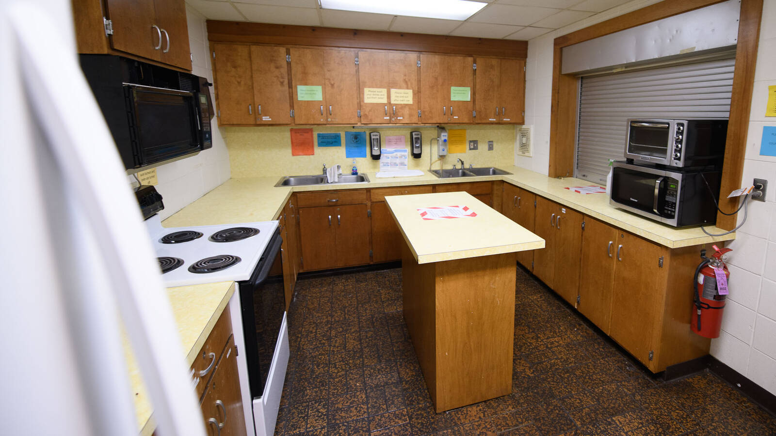 Kitchen space in Governors Hall with a fridge, oven/stove, sinks, microwaves, cabinets, and counter space.