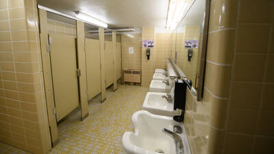 Governors Hall bathroom with toilet stalls, sinks, mirrors, and shower stalls.