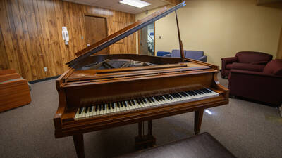 Common space in Governors Hall with chairs and a large piano.